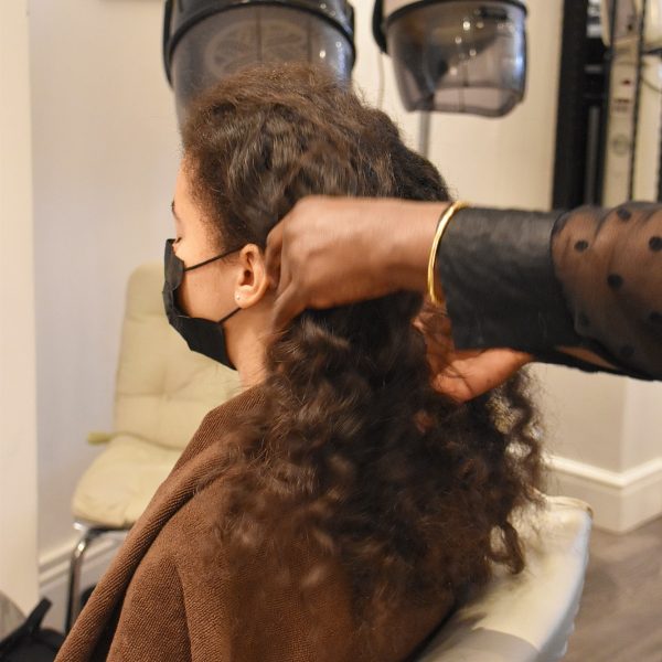 at the hair dresser, upbraiding afro hair, ready for a cut, with face mask on